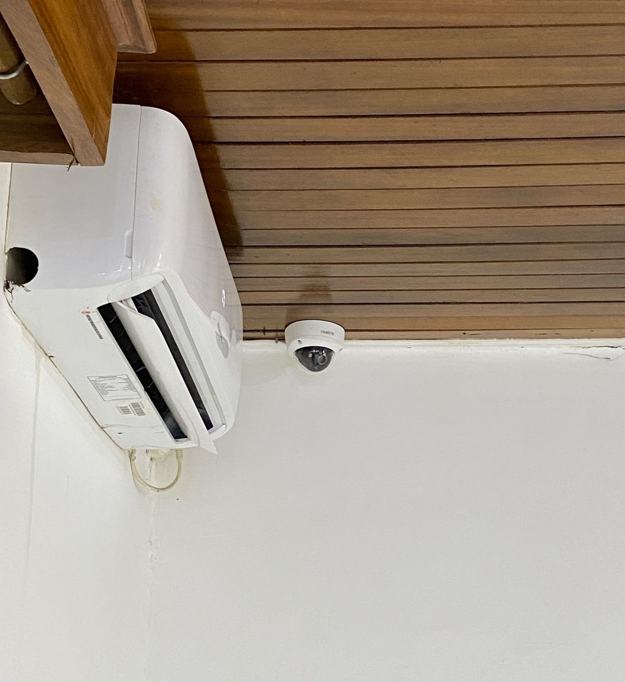 Caméra dôme intérieure installée en haut de mur, sous un plafond en lambris