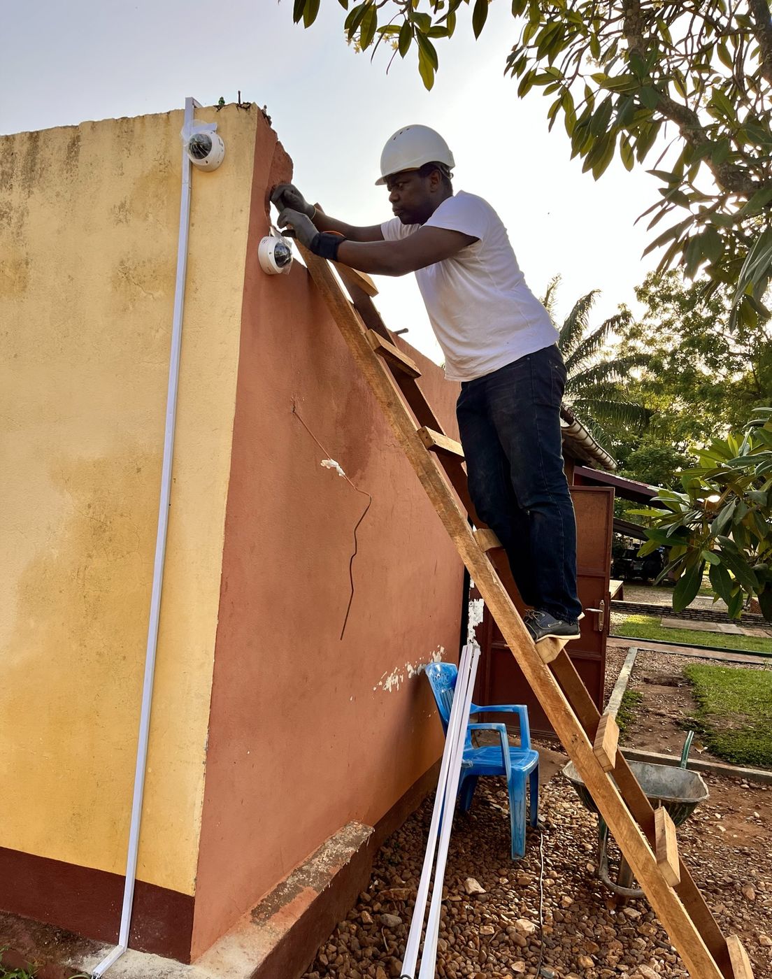 Technicien Canaan Network installant une caméra dôme en haut d'un mur de clôture